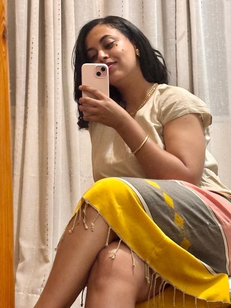 Sosi taking a relaxed mirror selfie wrapped in a woven blanket